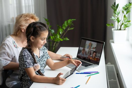 Grandmother and granddaughter using tablet and laptop