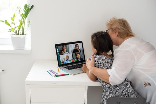 Happy grandmother and her granddaughter having video chat via laptop together at home.