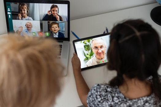 Cute little girl with her grandmother looking at tablet at home.