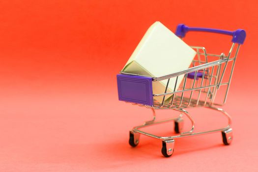 Shopping cart and giftboxes on pink background