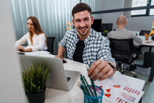 Portrait of young man sitting and working at his desk in the office, close up