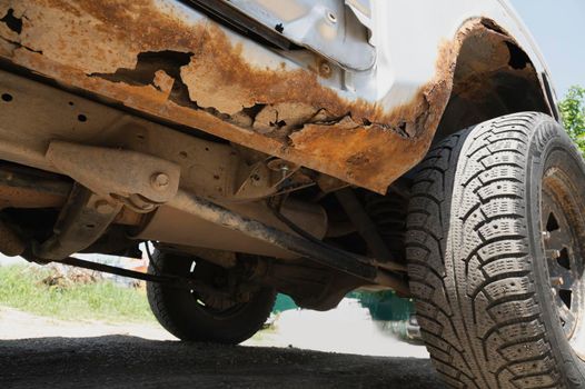 Deep rust on the body of a gray old car. Rust and corrosion hole on old worn out painted metal surface. Body parts repair. Need for repair