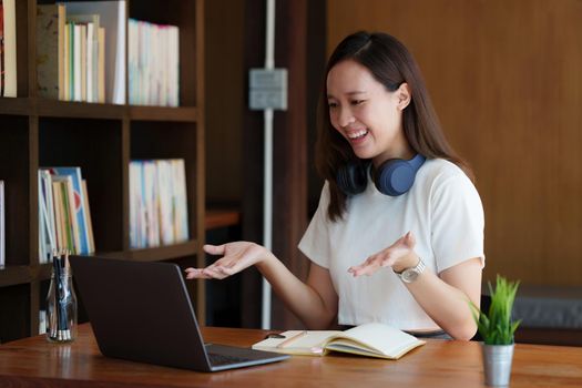 Image of Young woman with a headset working online on laptop computer. studying or working from home online concept