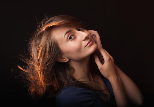 Studio romantic portrait of a young woman on dark background