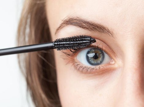 Woman applying mascara on her eyelashes