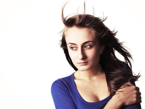 Portrait of a beautiful young woman with hair flying isolated on white with copy-space. High-contrast image with intentional color shift
 