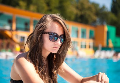 Young beautiful woman sunbathing near the pool