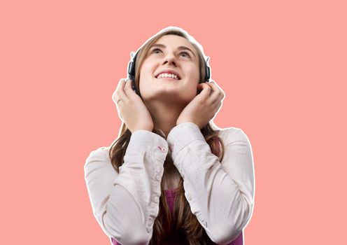 Lifestyle concept. Young happy woman listening to music on headphones. Magazine style collage with copy space and trendy coral color background