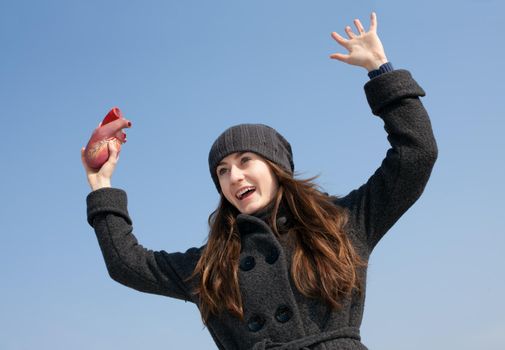 Young woman with a heart in her hand against the blue sky