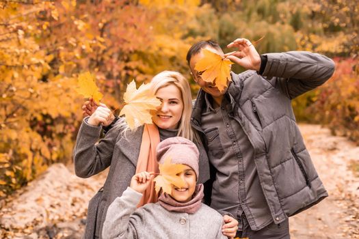 A Family of four enjoying golden leaves in autumn park.