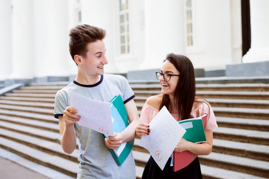 Two happy students have received excellent result of final test, look at each other and can`t believe their eyes that they have got the highest A grade