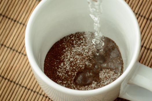 Pouring boiling water to the cap with coffee and sugar