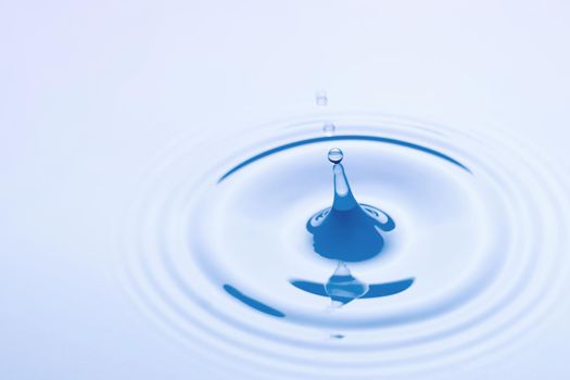 Studio shot of a water drop falling into a water making circles