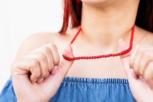 stylish young woman wearing jeans shirt, sunglasses and red jewelry at street, white wall background, summer look, copy space