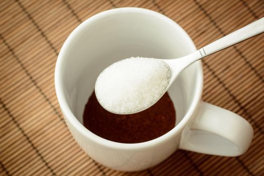 Holding sugar over the cup with coffee