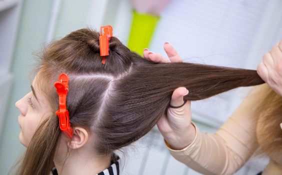 Close-up of the master's hand making a ponytail on a woman's head. The hairdresser makes a hairstyle for a young woman. Barber shop, business concept. Beauty salon, hair care.