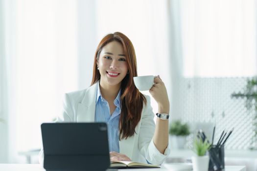 Portrait of an Asian businesswoman or business owner taking a coffee break while working in the office.