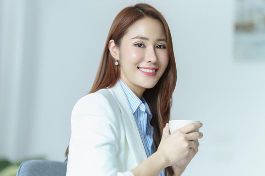 Portrait of an Asian businesswoman or business owner taking a coffee break while working in the office.