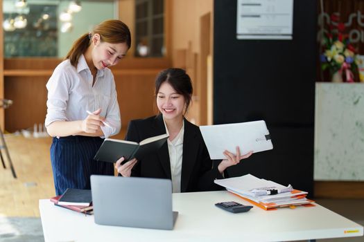 A portrait of two young Asian businesswoman plan marketing strategies and investments to profit from their clients.