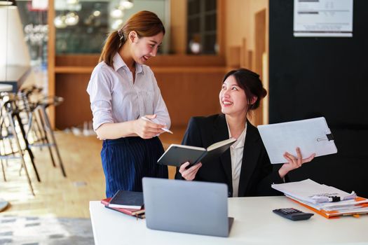 A portrait of two young Asian businesswoman plan marketing strategies and investments to profit from their clients.