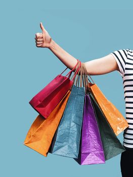 Commerce and shopping season. Happy young woman with paper shopping bags shows thumb up