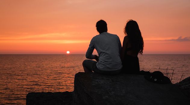 Romantic scene. Silhouette of a young couple in love on the background of sea sunset