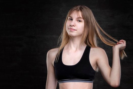 Teenage girl in a sports shirt on a dark background.