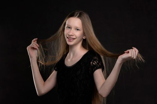 Beautiful teenager girl with long hair on a gray background.