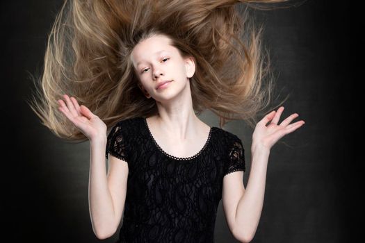 Beautiful teenager girl with flowing hair on a gray background.