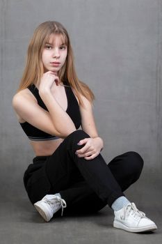 Plain teenage girl in sportswear on a gray background.