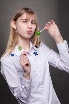 A funny and naughty teenager girl with a lollipop fooling around at the camera.