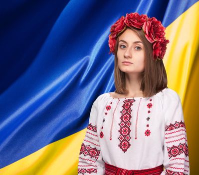 Patriotic concept.  Beautiful girl in the Ukrainian national suit against Ukrainian flag background