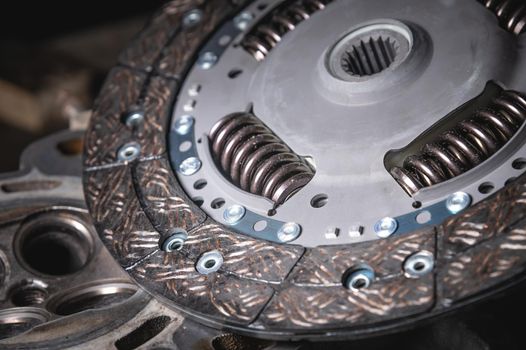 Close-up clutch disc of a car lies on metal parts contrast shot.