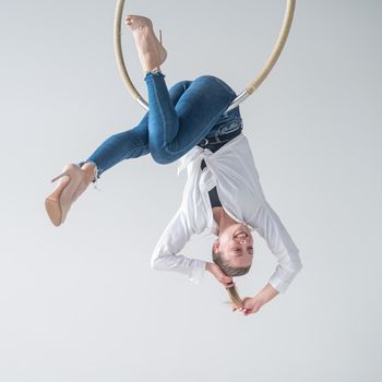 Caucasian woman in casual clothes on an aerial hoop