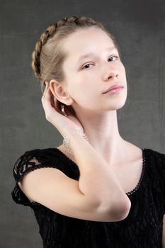 Beautiful teenager girl with a braid on a gray background.