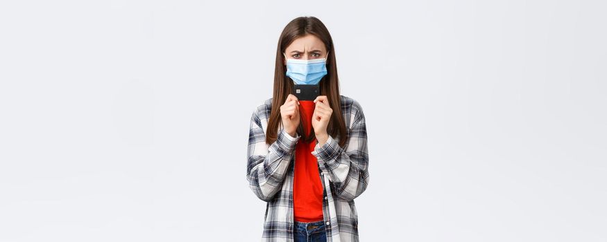 Coronavirus outbreak, working from home, online shopping and contactless payment concept. Angry or frustrated young woman in medical mask frowning displeased, holding credit card.