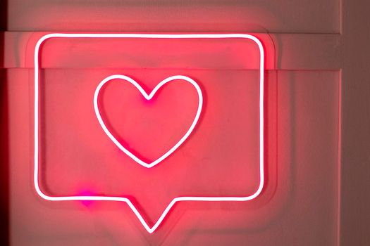 Bright luminous digital neon sign for a store or card beautiful shiny with a love heart. Glowing amour shape symbol passion in vivid colors. Valentines day concept.
