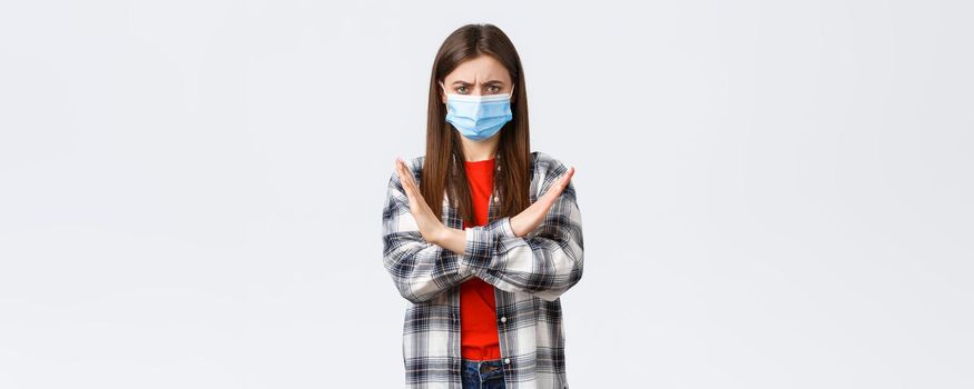 Coronavirus outbreak, leisure on quarantine, social distancing and emotions concept. Enough, this should stop. Serious displeased young woman in medical mask protest, show cross sign.