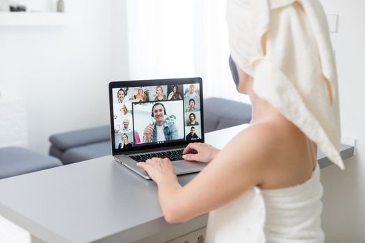 Mid adult woman in clay facial mask wearing bath towel using her laptop