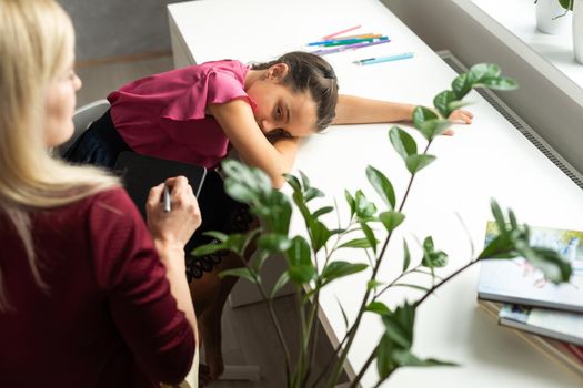 Female psychologist working with little girl at home.