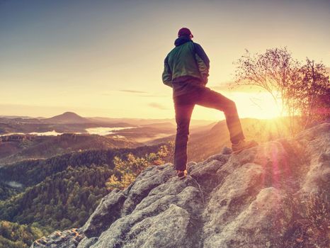 Traveler on mountain summit enjoying aerial view over misty countryside. Travel Lifestyle success adventur