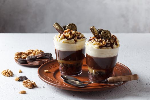 Delicious chocolate trifle or pudding with whipped cream in a glass on a gray background.