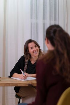 A female therapist in her office talking to a client to determine the best treatment for her health