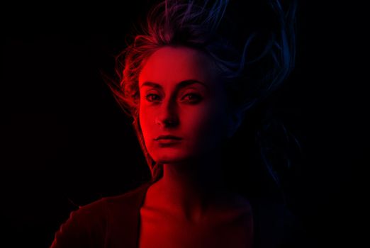 Studio romantic portrait of a young woman in dark red and blue tonality