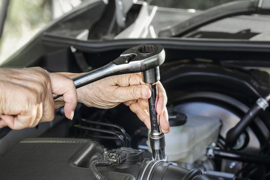 Elderly woman repairing her car