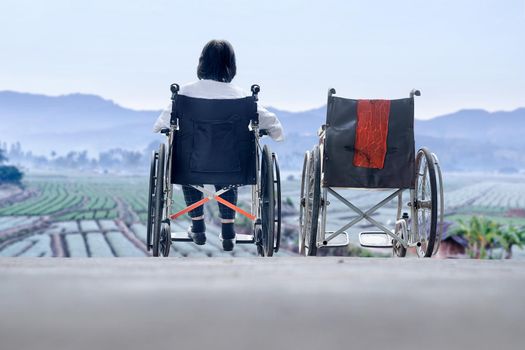 Elderly woman with empty wheelchair standing together