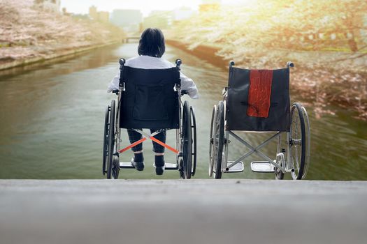 Elderly woman with empty wheelchair standing together