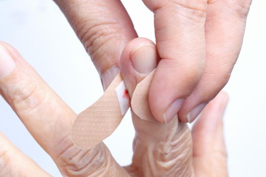 Nurse putting adhesive bandage on elderly woman hand