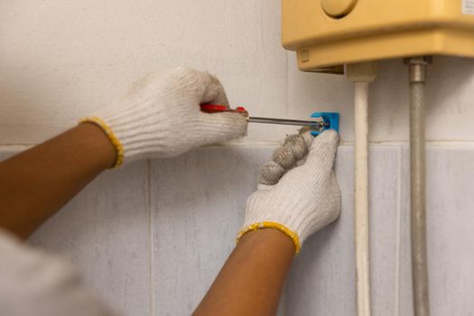 Worker installing floating pipeline on the wall in the old bathroom