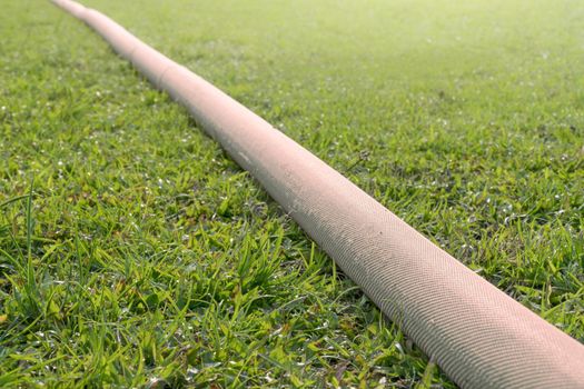 industrial hose in lawn of sport field.